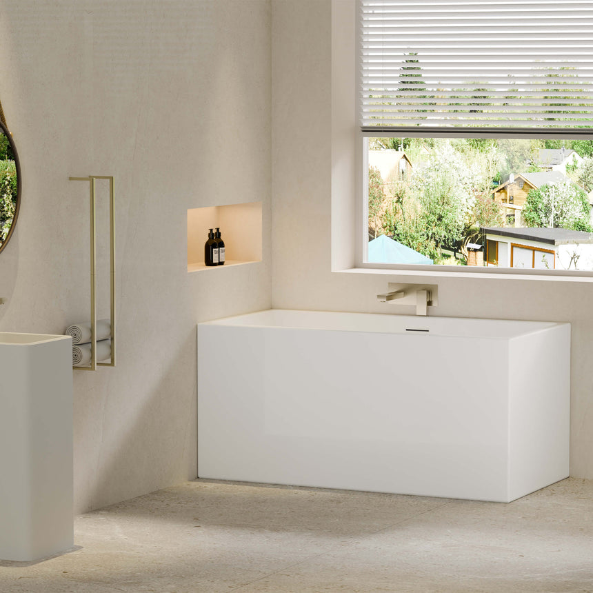 Crete 1350x680mm white freestanding bathtub by Tilemall positioned in ensuite bathroom interior with brass wall spout