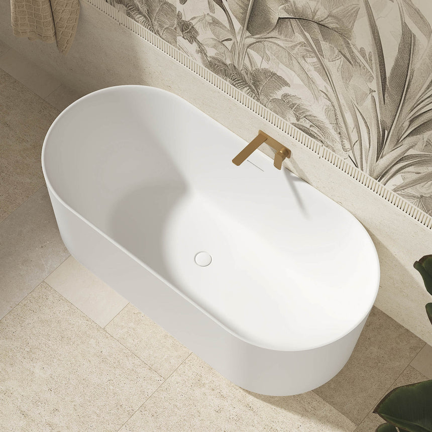 Otti Attica Celine matte white freestanding bath installed in modern ensuite with brass tap and botanical wallpaper by Tilemall