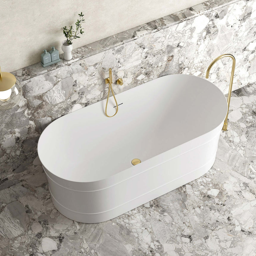 Otti Attica Bondi matte white freestanding bathtub installed in bathroom interior with marble wall and brass taps by Tilemall