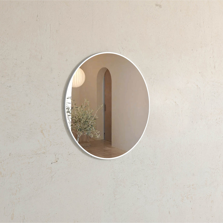 Otti 700mm round white framed mirror mounted on neutral wall in bathroom interior by Tilemall