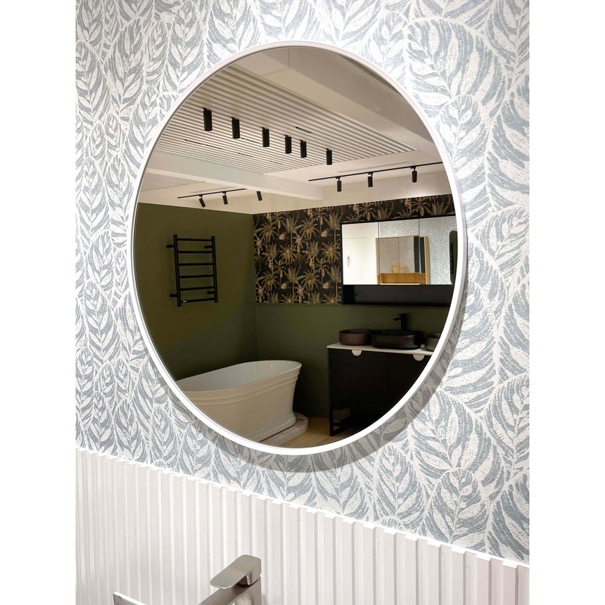 Otti 700mm round white framed mirror installed in bathroom with green walls and patterned wallpaper by Tilemall