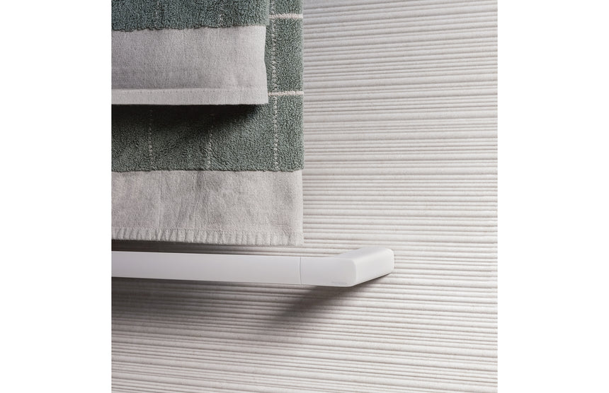 Phoenix Nuage towel rail in matte white mounted on textured wall tiles with folded towels draped over bar by Tilemall