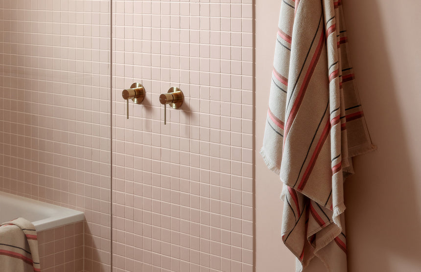 Phoenix Vivid Slimline brushed gold wall mixer installed on bathroom tile with lever handles by Tilemall