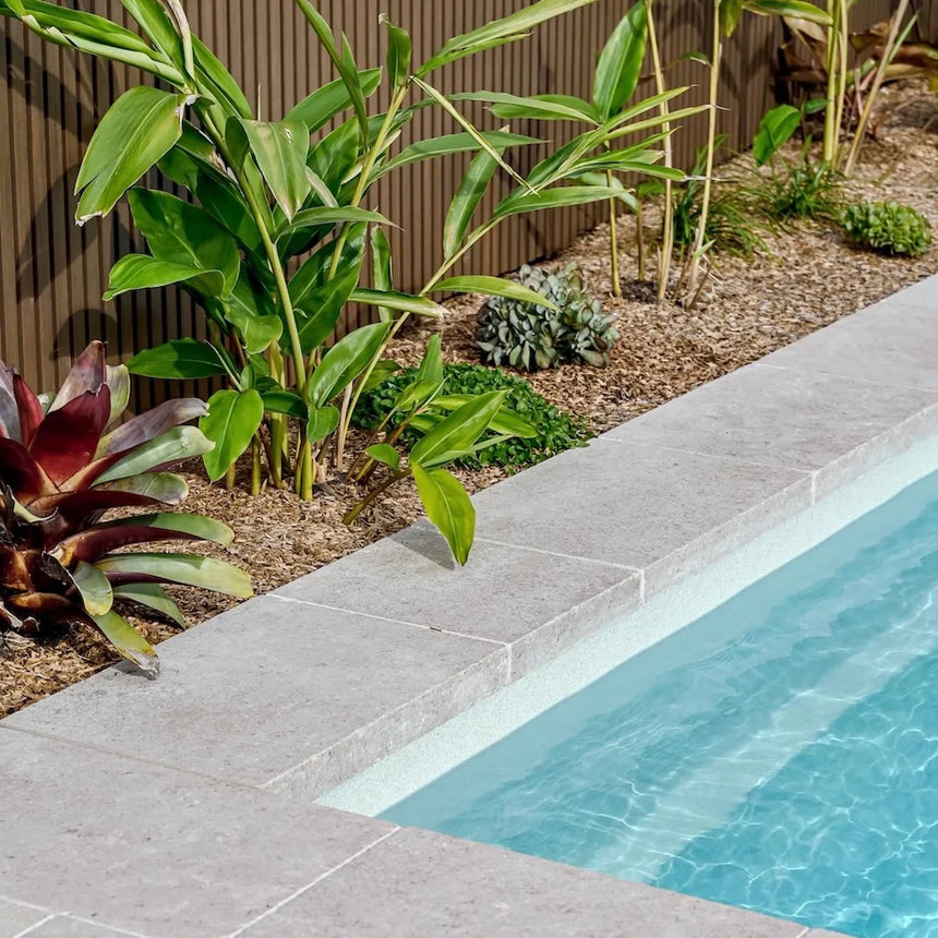 Avani Limestone crazy paving beside tropical plants and a pool by Tilemall
