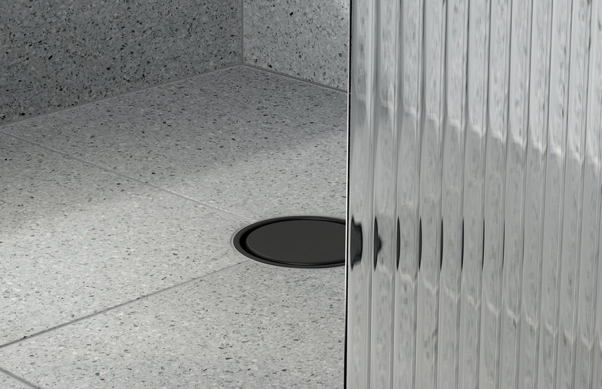 Phoenix Point Drain Round 100mm Outlet 90mm Matte Black, shown in a finished interior